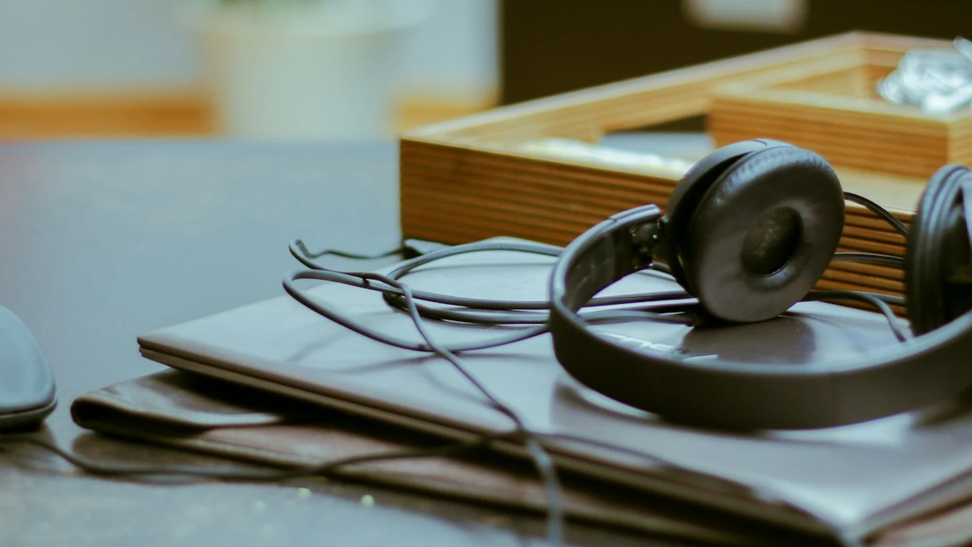Headphones resting on a laptop at a working desk