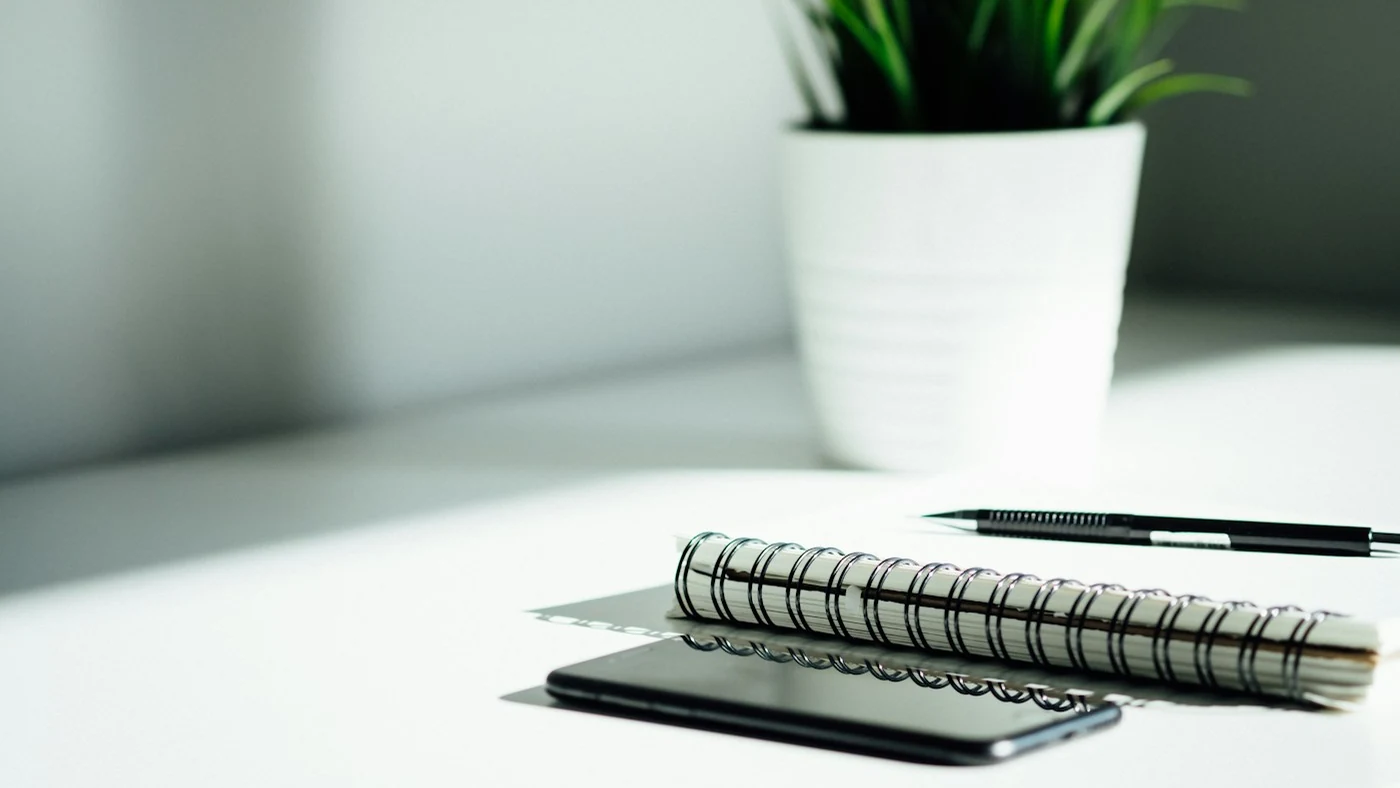 A notebook and phone on a sunlit desk