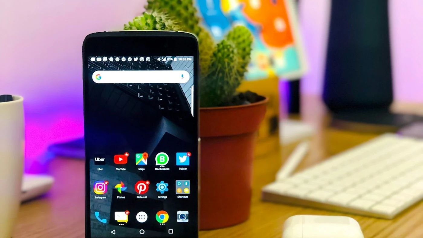 A smartphone on a desk beside a monitor