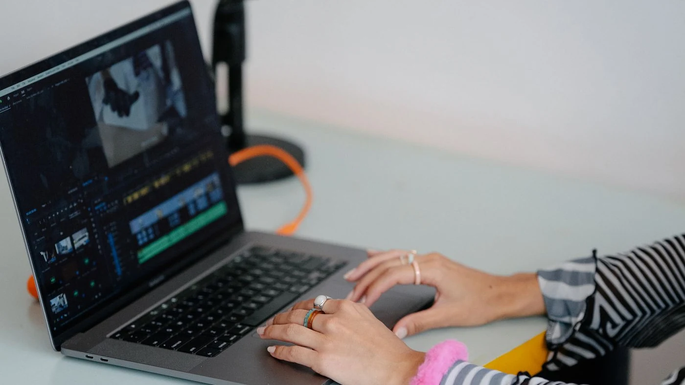 A creator editing footage on a laptop beside a microphone